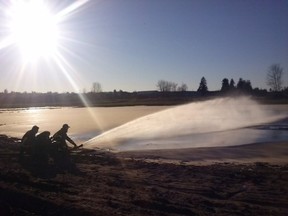 Firefighters help prepare a Surrey field for ice skating.
