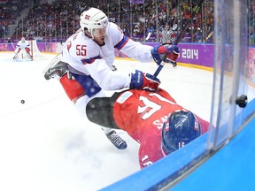 Jonathan Toews of Canada is checked by Norway's Ole-Kristian Tollefsen in their opening-round game at the Sochi Olympics on Feb. 13, 2014. Photo by Jean Levac, Postmedia News.