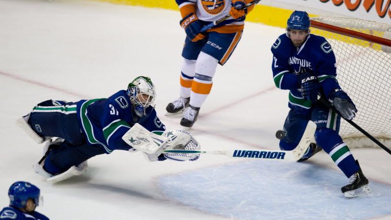 Vancouver Canucks defenceman Dan Hamhuis saves a New York Islanders shot with goalie Eddie Lack out of the net. CP photo.