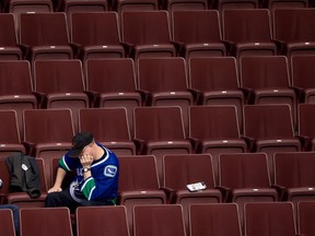 A Vancouver Canucks fan sits in the stands after the team gave up 7 goals to the New York Islanders in the third period and lost 7-4 during an NHL hockey game in Vancouver, B.C., on Monday March 10, 2014. THE CANADIAN PRESS/Darryl Dyck