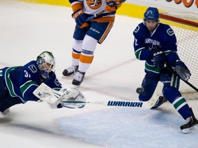 Vancouver Canucks' goalie Eddie Lack, dives to make the save as Dan Hamhuis covers the empty net during third period NHL hockey action against the New York Islanders in Vancouver, on Monday March 10, 2014. THE CANADIAN PRESS/Darryl Dyck