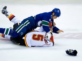 The Vancouver Canucks' Kevin Bieksa and the Calgary Flames' Mark Giordano tangle on March 8, 2014. CP file photo.