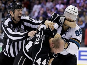 Linesman Pierre Racicot tries to break up a fight between Los Angeles Kings defenceman Robyn Regehr and San Jose Sharks right winger Brent Burns during Game 4.