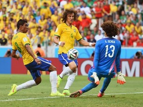 Paulinho of Brazil shoots against Guillermo Ochoa of Mexico as David Luiz runs on during the 2014 FIFA World Cup Brazil Group A match between Brazil and Mexico at Castelao on June 17, 2014 in Fortaleza, Brazil.  (Photo by Laurence Griffiths/Getty Images)