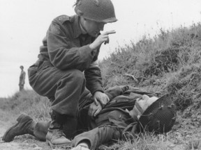 Canadian Chaplan Capt. Robert Seaborn giving absolution to a dying soldier near Caen, France, on July 15, 1944, nine days after D-Day. (NATIONAL ARCHIVES OF CANDA)