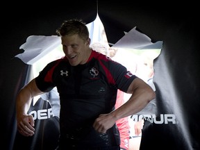 Rugby Canada men's team member John Moonlight bursts through a paper door as he shows off the team's new uniform at the team's practice facility in Burnaby, B.C. Tuesday, June, 3, 2014. THE CANADIAN PRESS/Jonathan Hayward ORG XMIT: JOHV109
