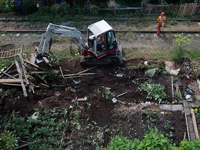 Workers destroy and remove community gardens from a stretch of abandoned CP Rail line in Vancouver, B.C., on Thursday August 14, 2014.