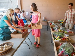 Customers load bags with their CSA box items delivered by Cara Abrahams, centre right and her husband Andy, right.