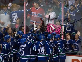 Vancouver Canucks' Daniel Sedin, of Sweden, is mobbed by his teammates after scoring the winning goal against the Montreal Canadiens during overtime NHL hockey action in Vancouver, B.C., on Thursday October 30, 2014. THE CANADIAN PRESS/Darryl Dyck