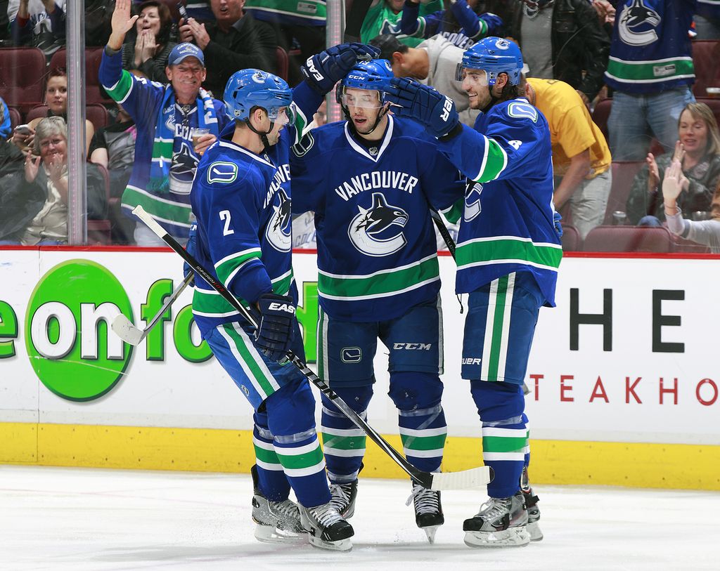 VANCOUVER, BC - OCTOBER 11: Nick Bonino #13 of the Vancouver Canucks is congratulated by teammates Dan Hamhuis #2 and Christopher Tanev #8 after scoring during their NHL game against the Edmonton Oilers at Rogers Arena October 11, 2014 in Vancouver, British Columbia, Canada.  Vancouver won 5-4 in a shootout. (Photo by Jeff Vinnick/NHLI via Getty Images)