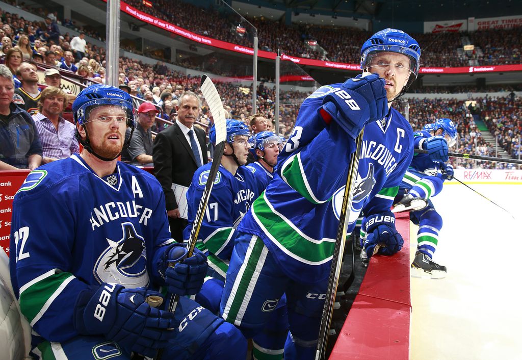 VANCOUVER, BC - OCTOBER 11: Daniel Sedin #22 of and Henrik Sedin #33 of the Vancouver Canucks look on from the bench during their NHL game against the Edmonton Oilers at Rogers Arena October 11, 2014 in Vancouver, British Columbia, Canada.  Vancouver won 5-4 in a shootout. (Photo by Jeff Vinnick/NHLI via Getty Images)