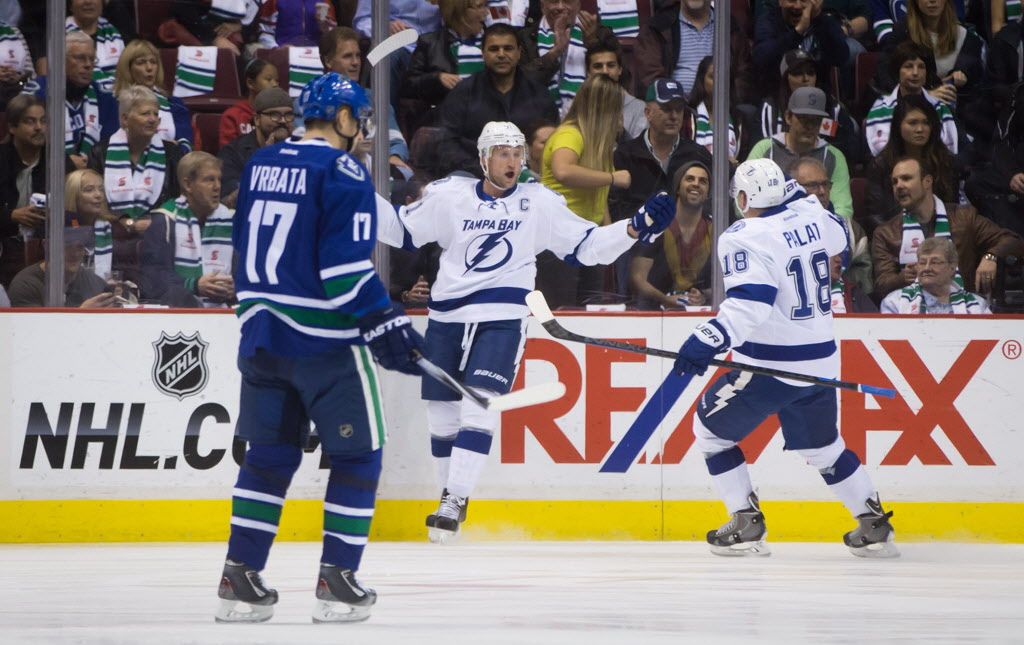 Tampa Bay Lightning's Steven Stamkos, centre, and Ondrej Palat, of the Czech Republic, celebrate Stamkos' first goal as Vancouver Canucks' Radim Vrbata, left, of the Czech Republic, looks on during the first period of an NHL hockey game in Vancouver, B.C., on Saturday October 18, 2014. THE CANADIAN PRESS/Darryl Dyck