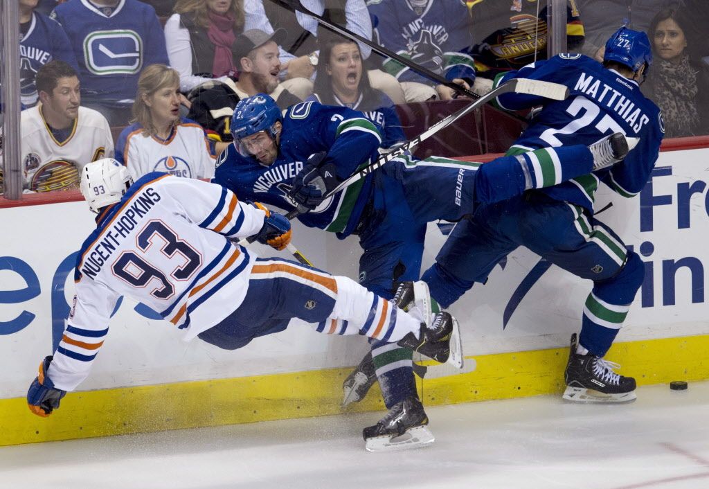 Vancouver Canucks defenceman Dan Hamhuis (2) goes into the boards as he hits Edmonton Oilers centre Ryan Nugent-Hopkins (93) as Canucks centre Shawn Matthias (27) looks for the puck during the third period of NHL action in Vancouver, B.C. Saturday, Oct. 11, 2014. THE CANADIAN PRESS/Jonathan Hayward
