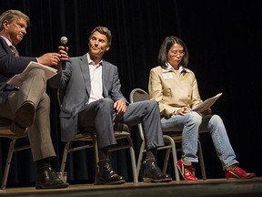 A grim-faced Vancouver mayor Gregor Robertson passes the microphone to an equally grim NPA mayoral  candidate Kirk LaPointe during a mayoral debate at the Italian Cultural Centre on Oct. 9, 2014. COPE mayoral candidate Meena Wong sits to their left.