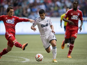Vancouver Whitecaps' Sebastian Fernandez, centre, of Uruguay, moves the ball past FC Dallas' Zach Loyd, left, during the second half of an MLS soccer game in Vancouver, B.C., on Saturday October 4, 2014. THE CANADIAN PRESS/Darryl Dyck ORG XMIT: VCRD219