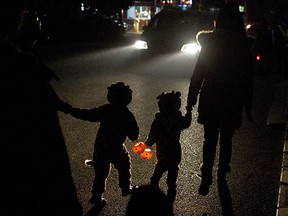 Two children dressed in their Halloween costumes hold pumpkin-shaped lanterns while walking on their way to ask for candies from neighbors the night before Halloween in Beijing, China, Wednesday, Oct. 30, 2013. (AP Photo/Alexander F. Yuan) ORG XMIT: XAY108