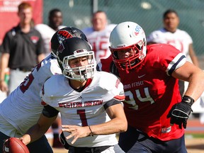 Western Oregon Wolves quarterback Ryan Bergman, pictured here eluding SFU’s Kristian Lawrence during a Sept. 13 game at Burnaby’s Swangard Stadium, threw two fourth-quarter TD passes Saturday to carry his team past the Clan 27-16 in Monmouth, Oregon. (File photo — Ron Hole, SFU athletics)