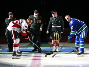 Henrik Sedin (right) and Erik Karlsson take a ceremonial faceoff celebrating Remembrance Day before their NHL game at Rogers Arena on Tuesday night.