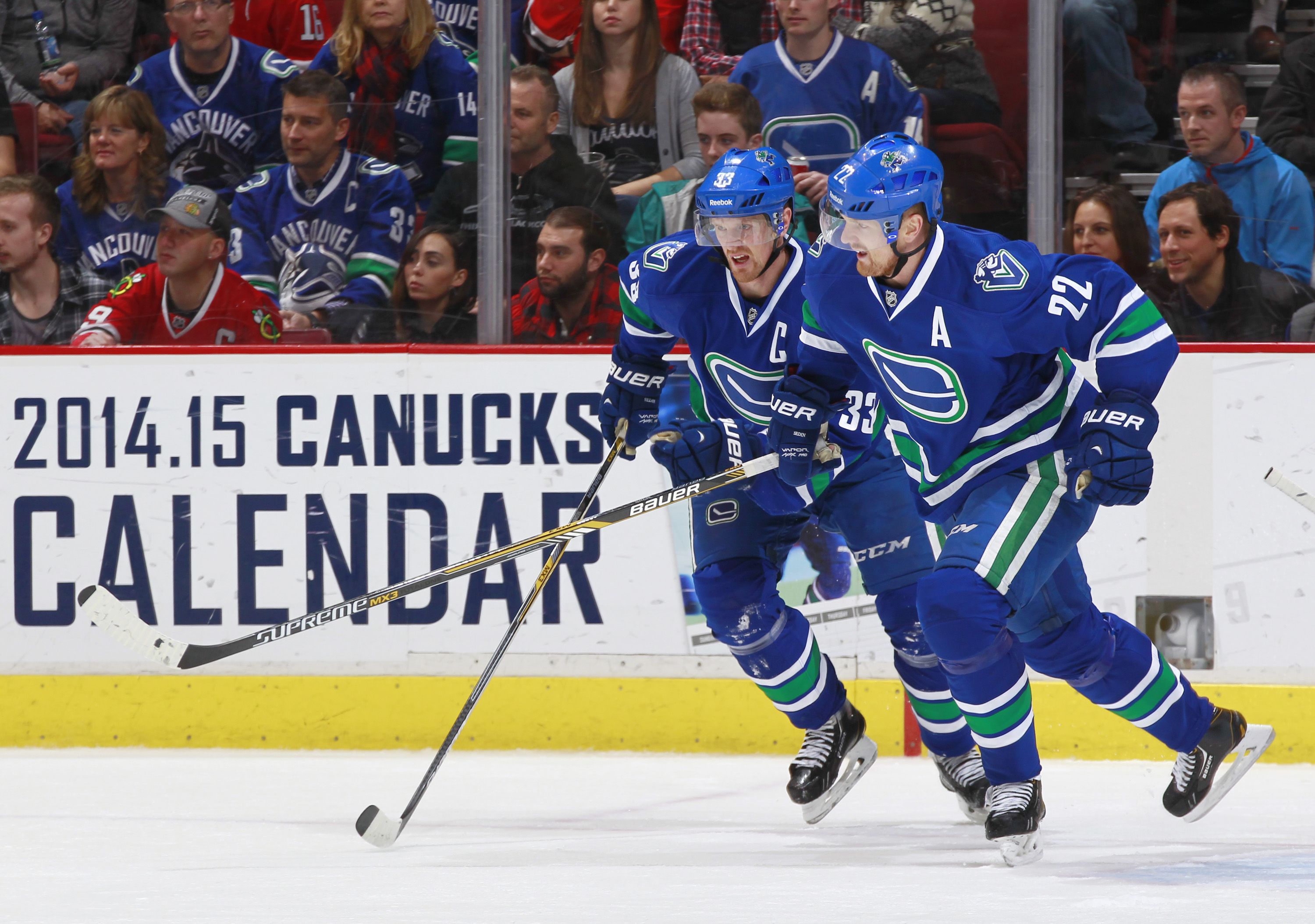 VANCOUVER, BC - NOVEMBER 23: Henrik Sedin #33 and Daniel Sedin #22 of the Vancouver Canucks break up ice against the Chicago Blackhawks during their NHL game at Rogers Arena November 23, 2014 in Vancouver, British Columbia, Canada. Vancouver won 4-1. (Photo by Jeff Vinnick/NHLI via Getty Images)