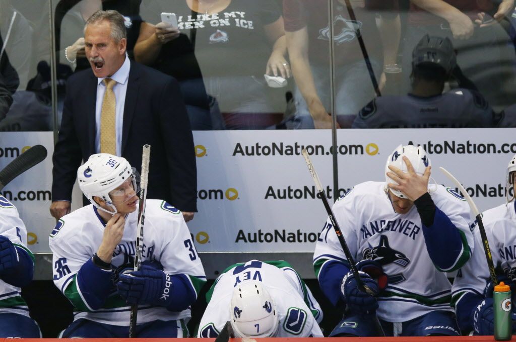 Vancouver Canucks head coach Willie Desjardins, back left, yells at his players on the bench as they face the Colorado Avalanche in the first period of an NHL hockey game in Denver, Friday, Oct. 24, 2014. (AP Photo/David Zalubowski)