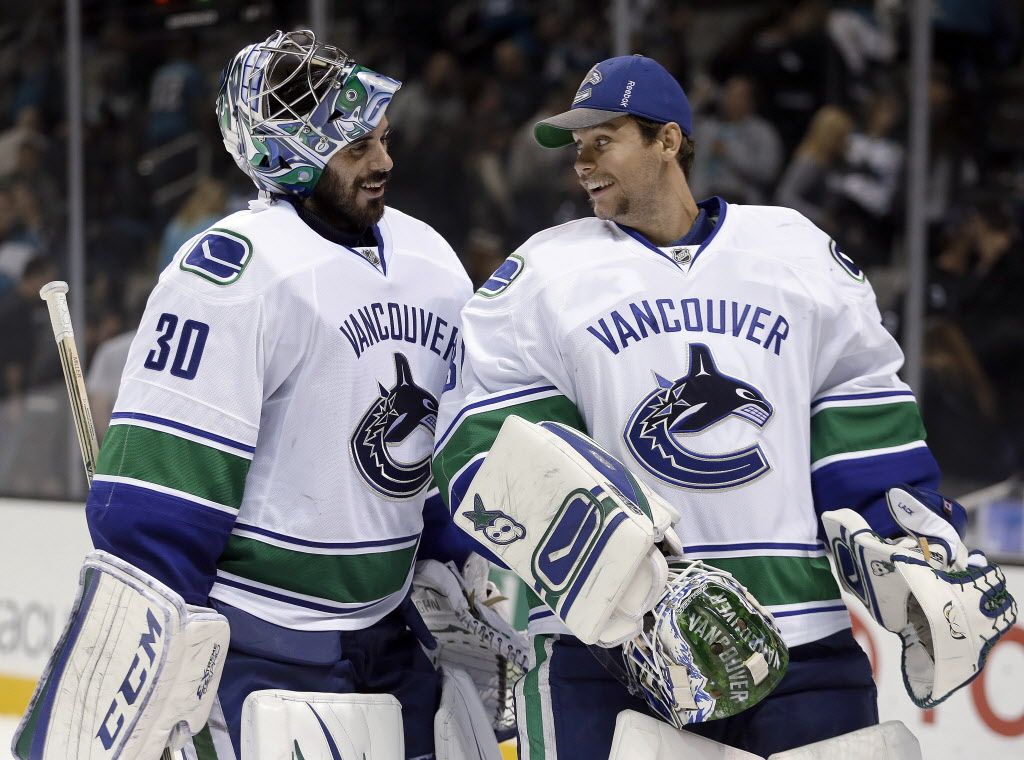 Vancouver Canucks goalies Ryan Miller, left, and Eddie Lack smile at the end of an NHL hockey game against the San Jose Sharks on Thursday, Nov. 6, 2014, in San Jose, Calif. Vancouver won 3-2. (AP Photo/Ben Margot)