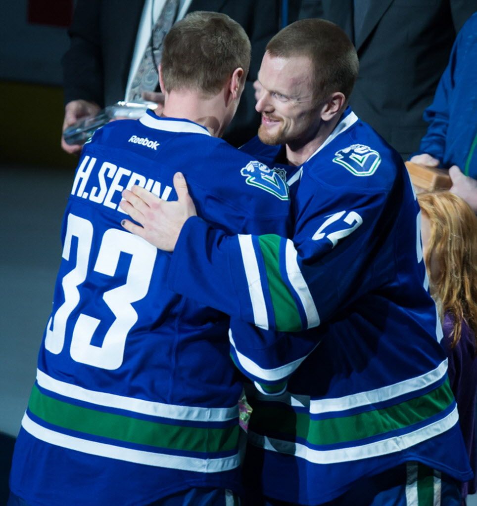 Vancouver Canucks' Henrik Sedin, left, congratulates his twin brother Daniel Sedin, both of Sweden, during a ceremony marking Daniel's 1,000th NHL game before an NHL hockey game against the Chicago Blackhawks in Vancouver, B.C., on Sunday November 23, 2014. THE CANADIAN PRESS/Darryl Dyck