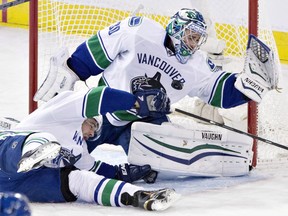 Vancouver Canucks goalie Ryan Miller (30) makes the save as Dan Hamhuis (2) defends against the Edmonton Oilers during third period NHL hockey action in Edmonton on Wednesday November 19, 2014. THE CANADIAN PRESS/Jason Franson