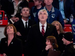 Former Vancouver Canucks' president and general manager Pat Quinn, centre, team president Trevor Linden, second left, and goalie Eddie Lack, right, of Sweden, watch a video tribute before Quinn's induction into the team's Ring of Honour before an NHL hockey game against the Calgary Flames in Vancouver, B.C., on Sunday April 13, 2014. THE CANADIAN PRESS/Darryl Dyck