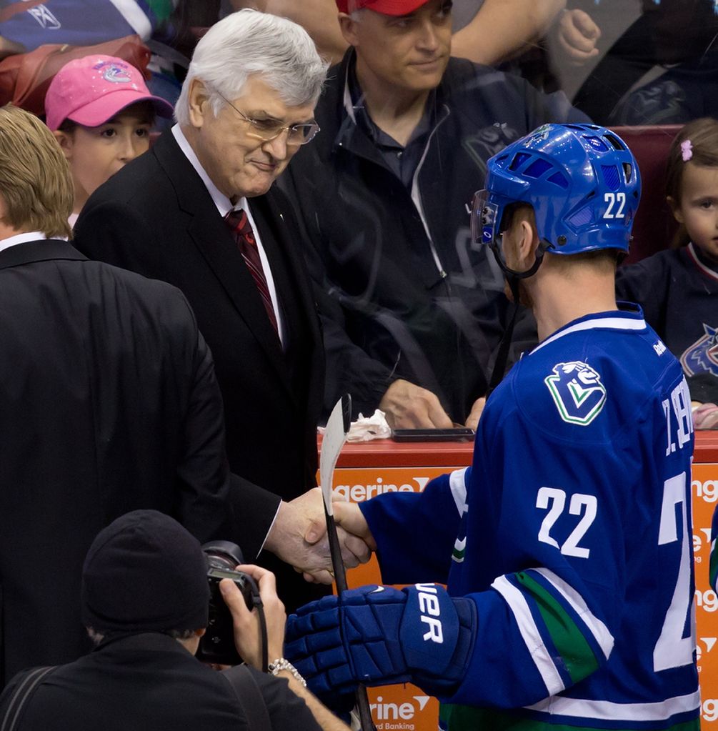 Former Vancouver Canucks' president and general manager Pat Quinn, left, shakes hands with Daniel Sedin, of Sweden, as he leaves the ice after being inducted into the team's Ring of Honour before an NHL hockey game against the Calgary Flames in Vancouver, B.C., on Sunday April 13, 2014. THE CANADIAN PRESS/Darryl Dyck ORG XMIT: VCRD209