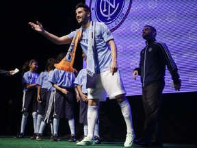 Spanish soccer star David Villa tosses team memorabilia to soccer fans while wearing the jersey to be worn by players in Major League Soccer's new team, New York City Football Club, during an introductory celebration,  Thursday, Nov. 13, 2014, in New York. New York City FC will play its first game at Yankee Stadium in March. (AP Photo/Julie Jacobson)