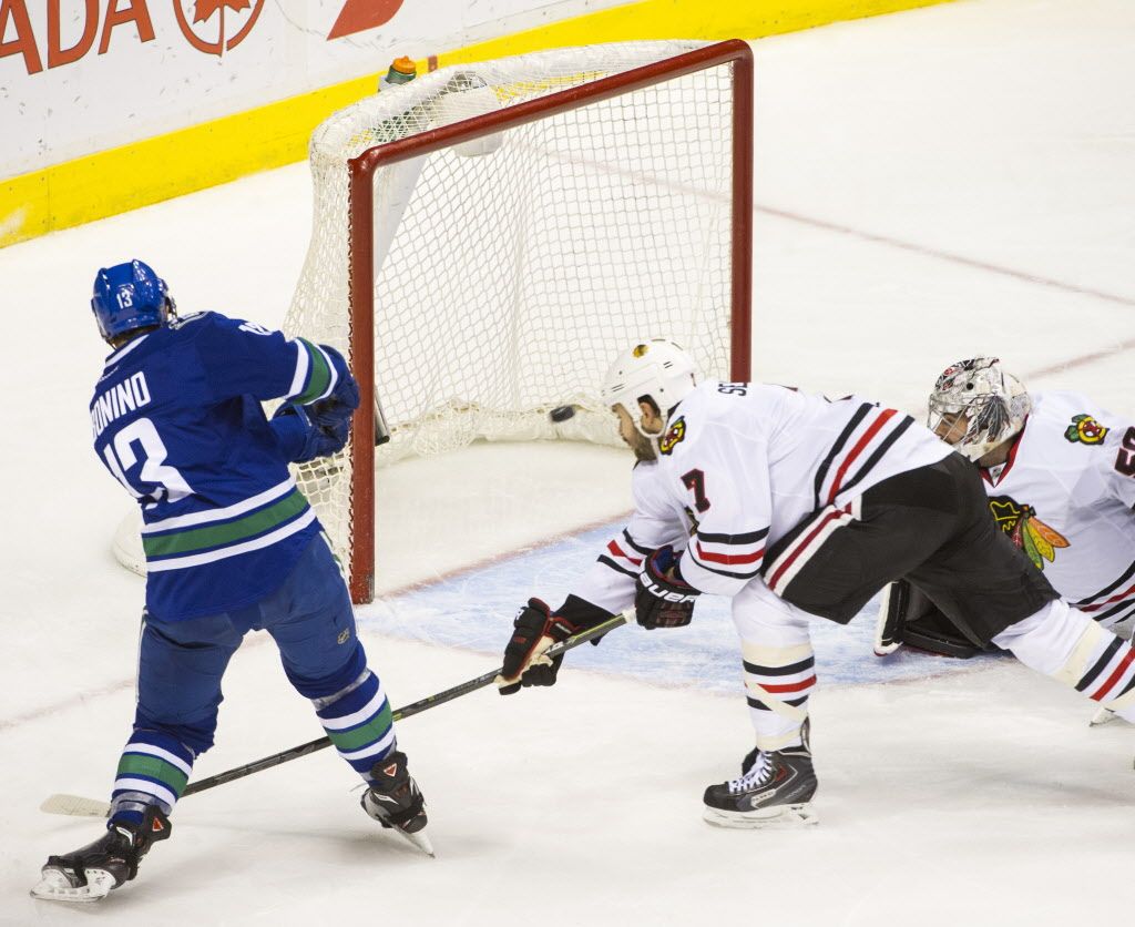 VANCOUVER, BC: NOVEMBER 23, 2014 -- Vancouver Canucks Nick Bonino, left misses the open net behind Chicago Blackhawks Brent Seabrook, centre and goalie Corey Crawford, right during the third period of an regular-season NHL game at Rogers Arena in Vancouver, B.C. Sunday November 23, 2014.   (Ric Ernst / PNG)  (Story by sports)  TRAX #: 00033197A & 00033197B [PNG Merlin Archive]