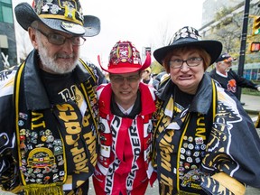 Hamilton Tiger-Cats fans Hugh Harrison, left and his wife Donna Harrison, right flank Calgary Stampeders fan Cheryl Graham, centre as the trio put their game faces on for the camera near the Telus Street Festival in downtown Vancouver, B.C. Thursday November 27, 2014. The three friends are attending the 102nd Grey Cup Championship game featuring the Hamilton Tiger-Cats and the Calgary Stampeders on Sunday at BC Place Stadium.  (Ric Ernst / PNG)