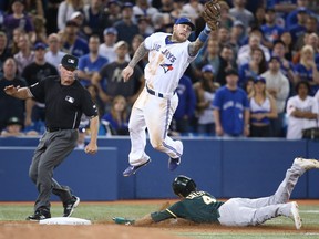 Coco Crisp #4 of the Oakland Athletics steals third base in the ninth inning during MLB game action as Brett Lawrie #13 of the Toronto Blue Jays jumps for the high throw on May 23, 2014 at Rogers Centre in Toronto, Ontario, Canada. (Photo by Tom Szczerbowski/Getty Images)