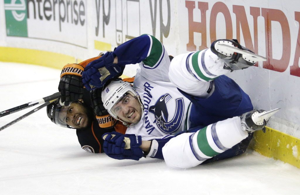 Vancouver Canucks' Chris Tanev, front, and Anaheim Ducks' Devante Smith-Pelly fall to the ice in overtime of an NHL hockey game Sunday, Dec. 28, 2014, in Anaheim, Calif. The Ducks won 2-1. (AP Photo/Jae C. Hong)