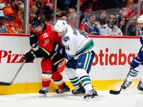 TJ Brodie of the Flames tries to get away from Alex Burrows of the Canucks during the season opener on Oct. 8. Both teams are trying to elude losing streaks -- they've dropped 12 games in a row combined.  (Photo by Gerry Thomas/NHLI via Getty Images)