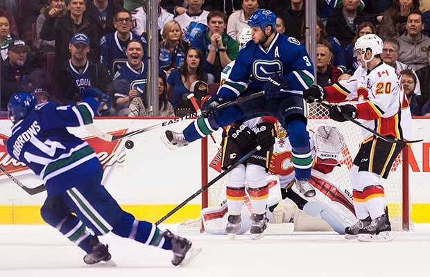 Kevin Bieksa jumps to redirect an Alex Burrows shot against the Calgary Flames on Jan. 10.