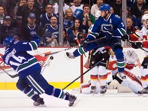 Kevin Bieksa jumps to redirect an Alex Burrows shot against the Calgary Flames on Jan. 10.