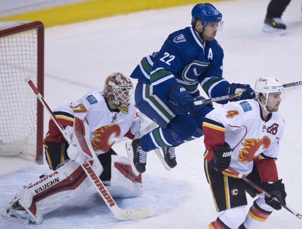 Vancouver Canucks left wing Daniel Sedin (22) jumps in front of Calgary Flames goalie Joni Ortio (37) as Calgary Flames defenseman Kris Russell (4) keeps his eye on the puck during third period NHL action in Vancouver on Saturday, Jan.10, 2015. THE CANADIAN PRESS/Jonathan Hayward