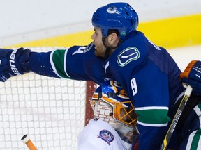 Vancouver Canucks' Zack Kassian, right, is checked into New York Islanders' goalie Jaroslav Halak, of Slovakia, by Nick Leddy during the third period of an NHL hockey game in Vancouver, B.C., on Tuesday January 6, 2015. THE CANADIAN PRESS/Darryl Dyck