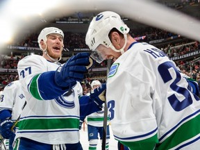 Shawn Matthias #27 and Henrik Sedin #33 of the Vancouver Canucks celebrate after defeating the Chicago Blackhawks 5-4 in overtime during the NHL game at the United Center on February 11, 2015 in Chicago, Illinois.