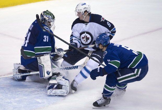 Vancouver Canucks defenseman Luca Sbisa (5) tries to clear Winnipeg Jets defenseman Jacob Trouba (8) from in front of Vancouver Canucks goalie Eddie Lack (31) during the second period of NHL action in Vancouver, B.C. Tuesday, Feb. 3, 2015. THE CANADIAN PRESS/Jonathan Hayward