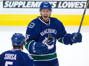 Vancouver Canucks' Alex Biega, right, and Luca Sbisa, of Switzerland, celebrate Biega's first NHL goal during the third period of an NHL hockey game against the Minnesota Wild in Vancouver, B.C., on Monday February 16, 2015. THE CANADIAN PRESS/Darryl Dyck