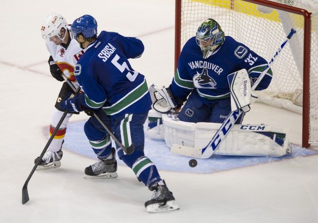 VANCOUVER September 26 2014. Vancouver Canucks #5 Luca Sbisa tangles with Calgary Flames #32 Paul Byron in front of the net as Vancouver Canucks goalie Joacim Eriksson stops a shot in the third period of a preseason NHL hockey game at Rogers Arena, Vancouver September 26 2014.   Gerry Kahrmann  /  PNG staff photo) ( For Prov / Sun Sports ) 00031988A [PNG Merlin Archive]