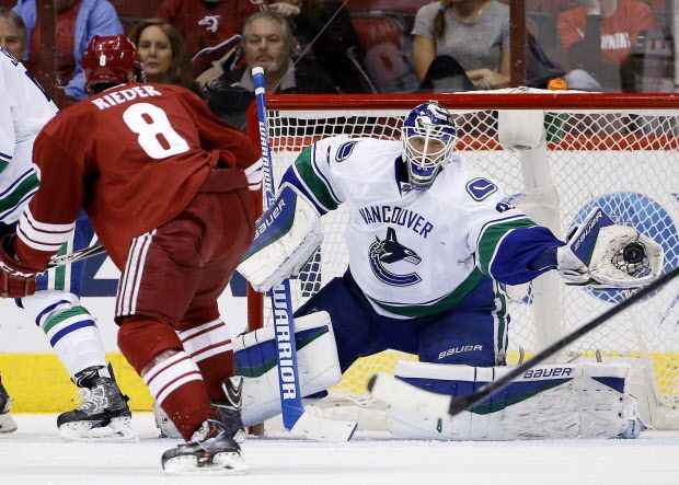 Vancouver Canucks' Jacob Markstrom, right, of Sweden, makes a save as Arizona Coyotes' Tobias Rieder (8), of Germany, looks on during the first period of an NHL hockey game Sunday, March 22, 2015, in Glendale, Ariz. The Canucks defeated the Coyotes 3-1. (AP Photo/Ross D. Franklin)