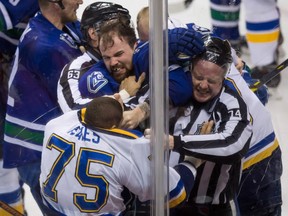 Vancouver Canucks' Zack Kassian, top, and St. Louis Blues' Ryan Reaves try to fight as linesmen Trent Knorr, back, and Lonnie Cameron, right, attempt to separate them during the second period of an NHL hockey game in Vancouver, B.C., on Sunday March 1, 2015. THE CANADIAN PRESS/Darryl Dyck