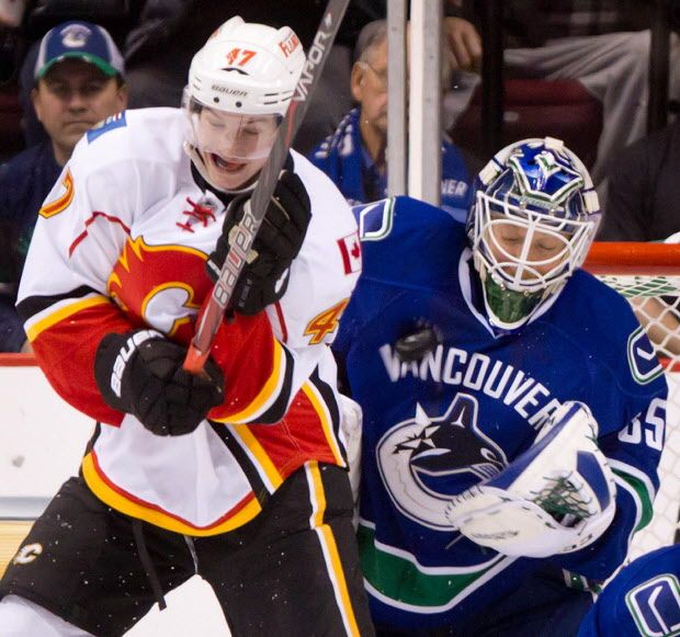 Vancouver Canucks goalie Cory Schneider, right, makes the save as Calgary Flames' Sven Baertschi, of Switzerland, screens him during the first period of an NHL hockey game in Vancouver, B.C., on Wednesday January 23, 2013. THE CANADIAN PRESS/Darryl Dyck ORG XMIT: VCRD101