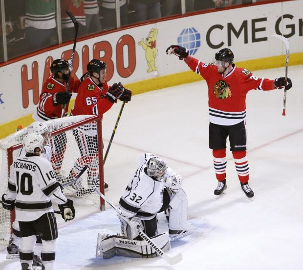 Chicago Blackhawks left wing Bryan Bickell, right, celebrates his goal with teammates Johnny Oduya (27) and Andrew Shaw (65) as Los Angeles Kings goalie Jonathan Quick (32) and Mike Richards (10) watch during the first period of an NHL hockey game Monday, March 30, 2015, in Chicago. (AP Photo/Charles Rex Arbogast)