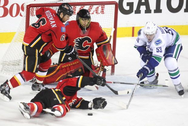 Colleen De Neve/ Calgary Herald CALGARY, AB --APRIL 21, 2015 -- Calgary Flames defenceman Kris Russell, on ground, blocked a shot as teammates defenceman Dennis Wideman and goalie Jonas Hiller kept an eye on the puck and Vancouver Canucks centre Bo Horvat during second period NHL playoff action in game 4 of the series at the Scotiabank Saddledome in Calgary on April 21, 2015.  (Colleen De Neve/Calgary Herald) (For Sports story by Scott Cruickshank) 00064432B SLUG: 0422-Flames Canucks Game ORG XMIT: A65W9108.JPG