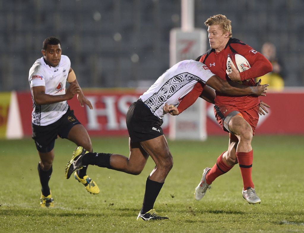 Canada's John Moonlight (R) is tackled by Fiji's Isake Katonibau (C) during the play-off for the third place of the Tokyo Rugby Sevens in Tokyo on April 5, 2015. Fiji defeated Canada 21-19.   AFP PHOTO / Toru YAMANAKA        (Photo credit should read TORU YAMANAKA/AFP/Getty Images)