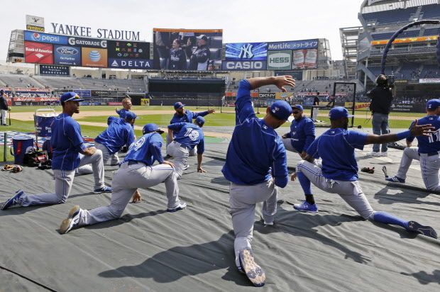 Toronto Blue Jays players stretch on a tarp on the field before an opening day baseball game against the New York Yankees in New York, Monday, April 6, 2015. (AP Photo/Kathy Willens)